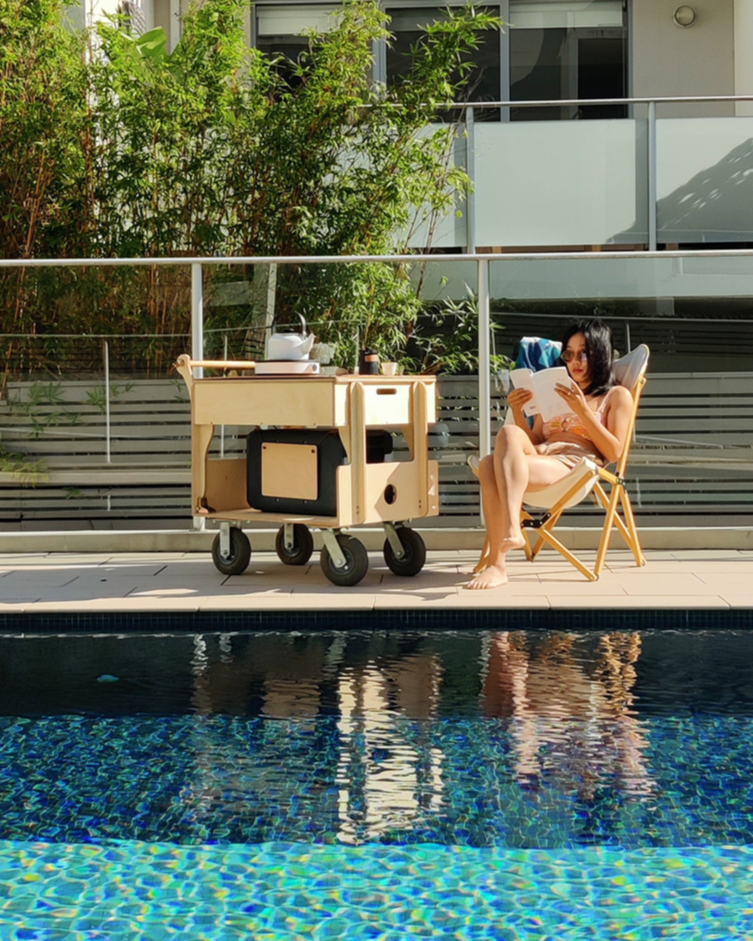 A person reading beside the Hearth and an apartment pool